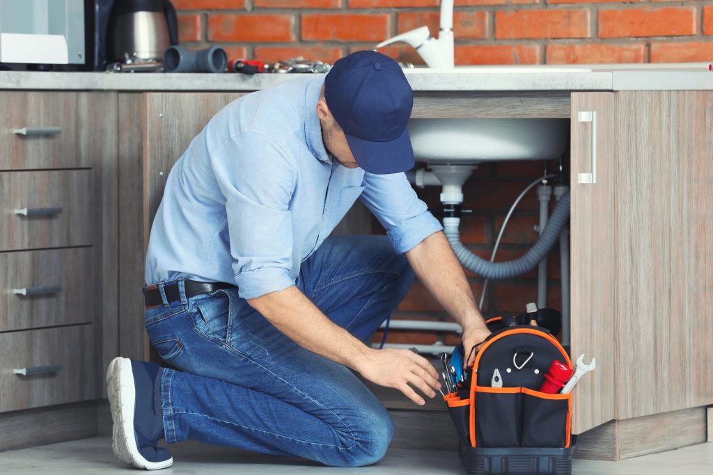 Professional plumber fixing kitchen sink